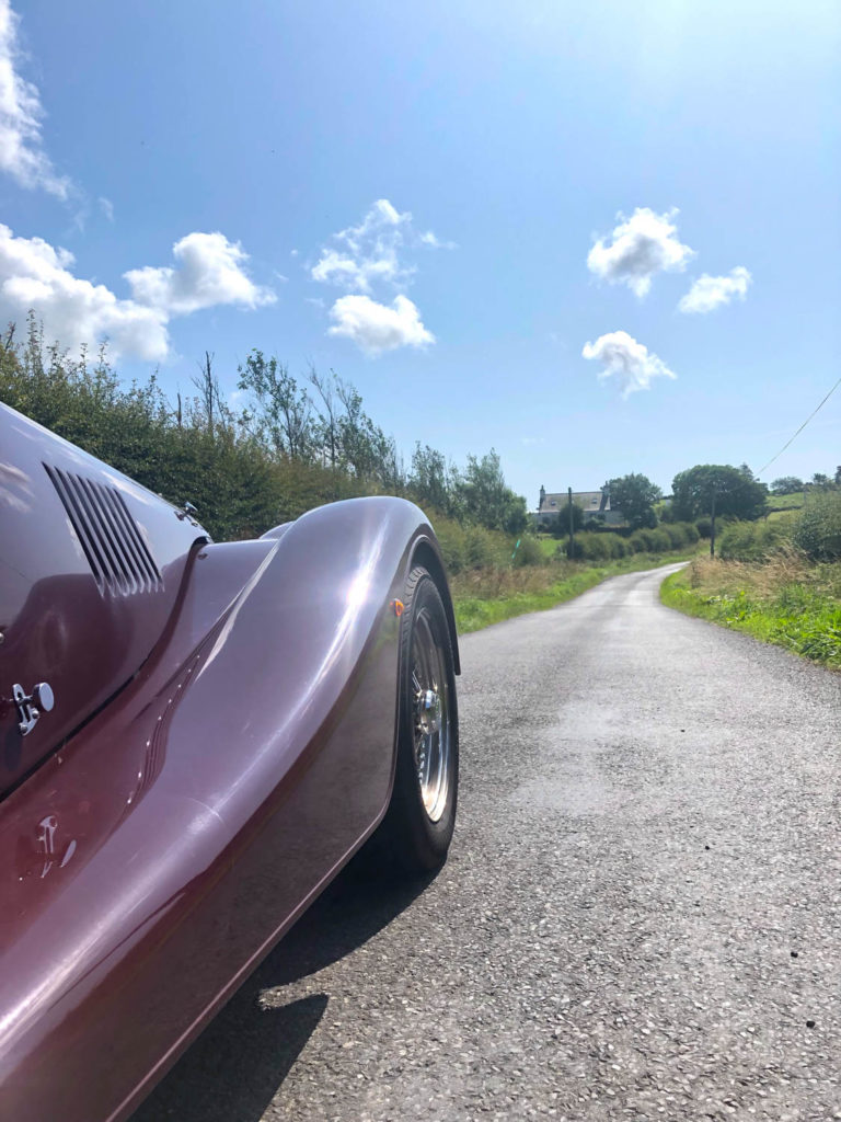 Side view of maroon car parked driving along road