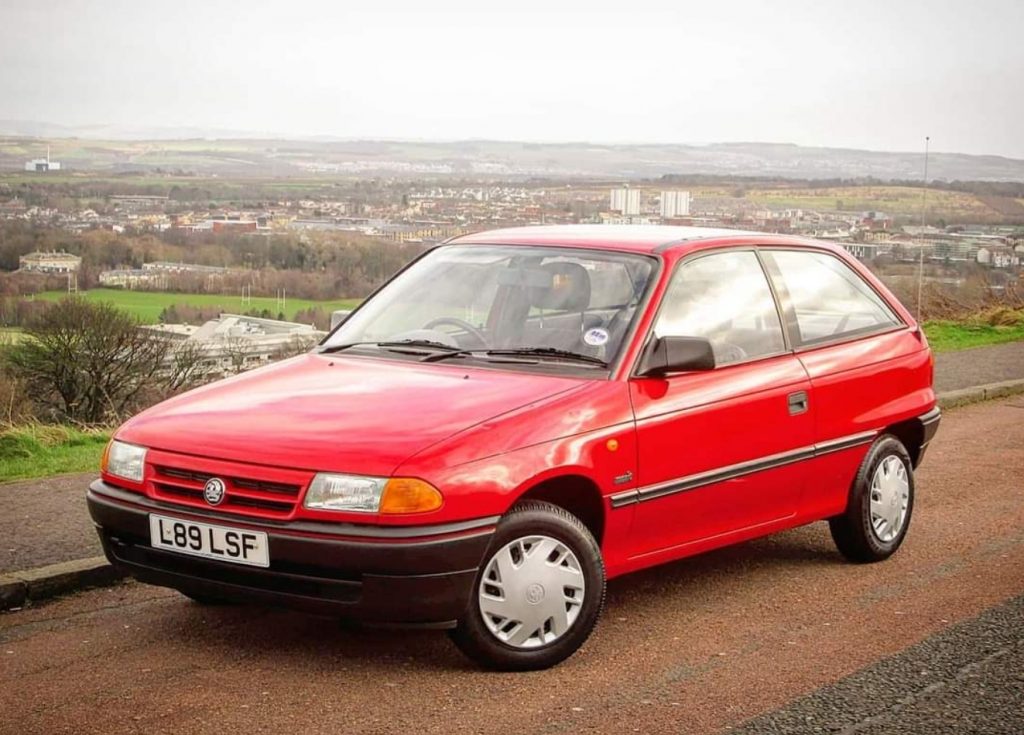 Front view of a red Vauxhall Astra parked on gravel track