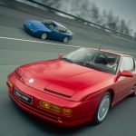A blue Alpine A610 and a red Alpine A610 driving side by side along a racing track