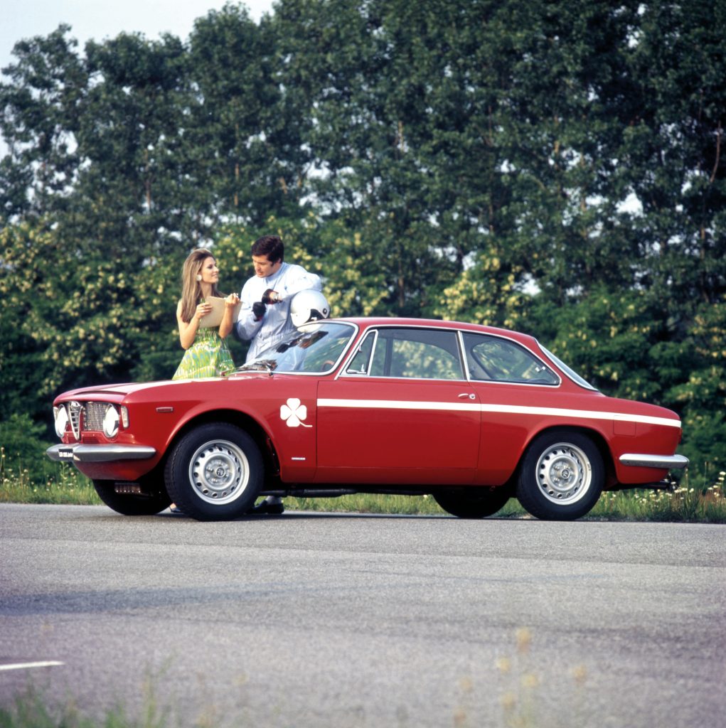 Man and woman standing next to Alfa Romeo GTA