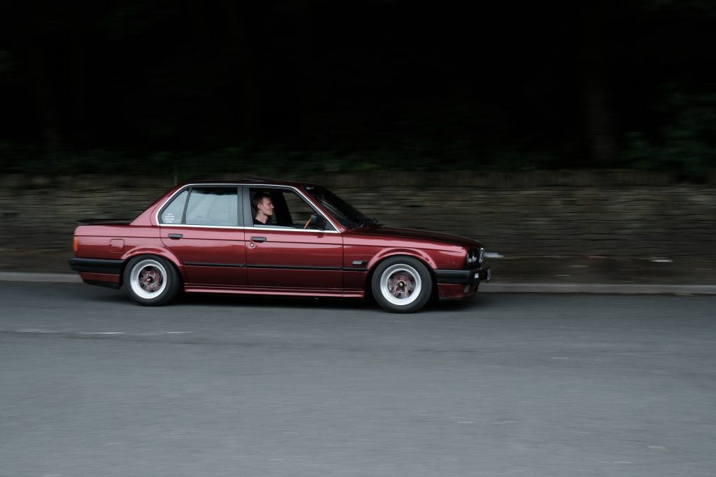 Red BMW E30 in driving on road