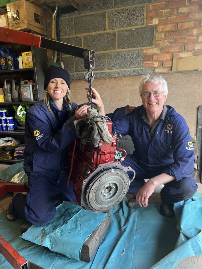 Two mechanics holding car engine
