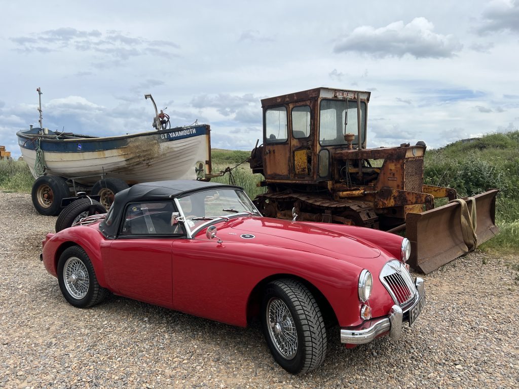 Red MGA Roadster parked on gravel
