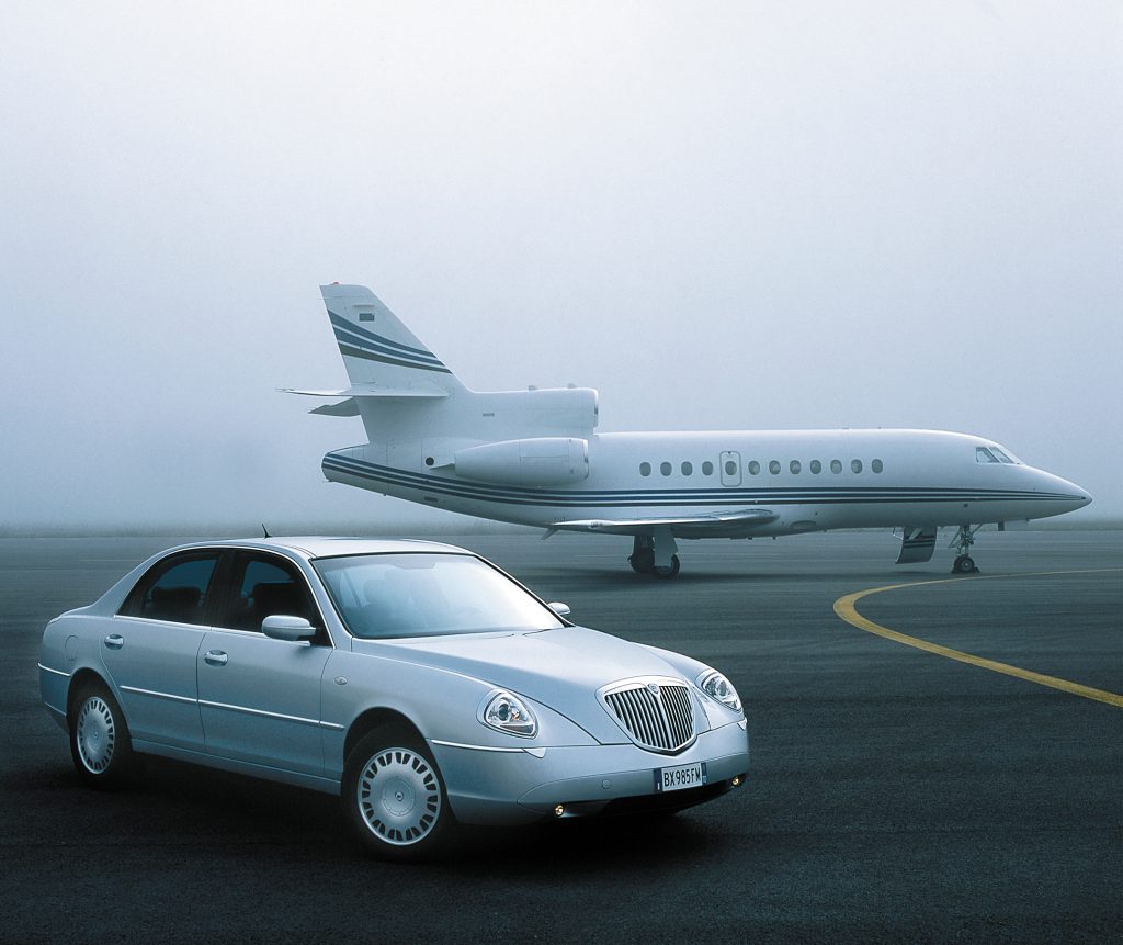 Car parked on taxiway in front of private jet
