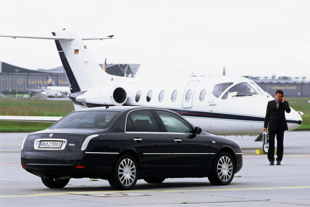 Car on taxiway in front of private jet