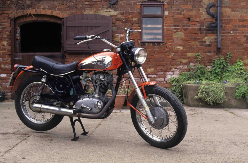 Ducati 350 Scramber parked in courtyard in front of red brick building