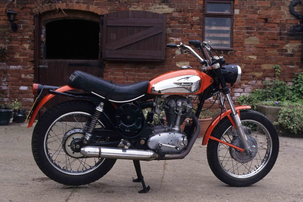Ducati 350 Scramber parked in courtyard in front of red brick building