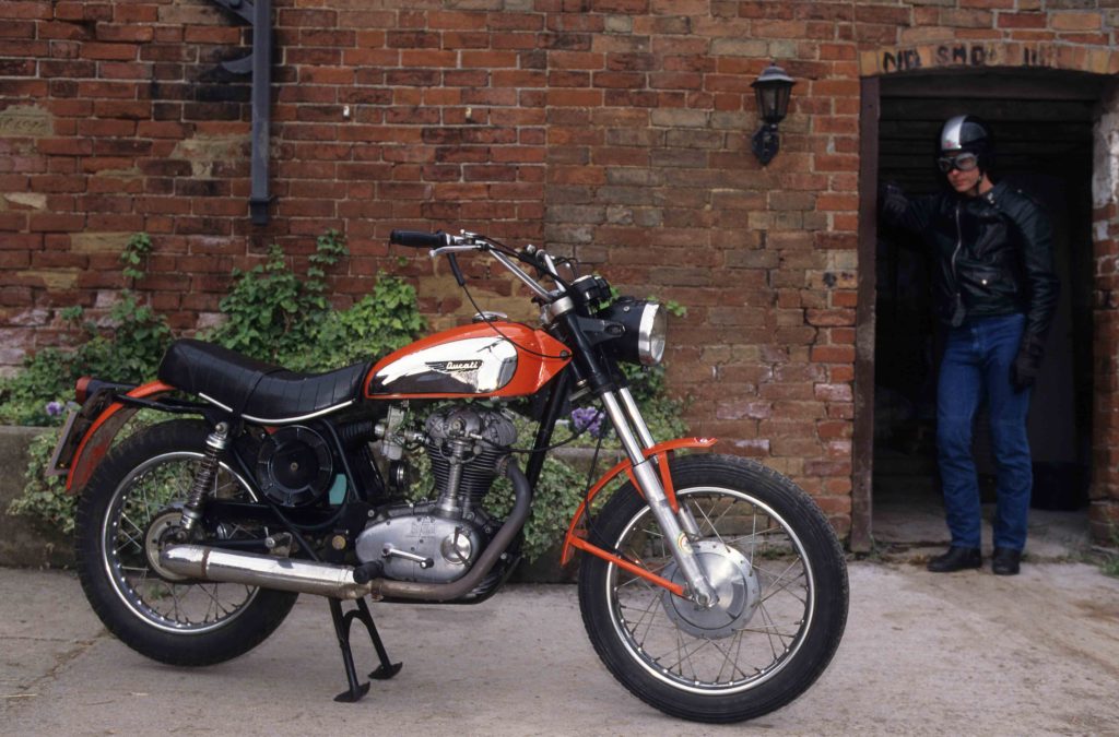 Red Ducati Scrambler 350 parked in front of brick building