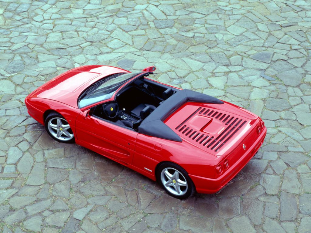 Top-down view of a convertible red car with the roof off, parked on flagstone ground 
