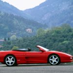 Side view of Ferrari F355 Spider parked with hills in the background