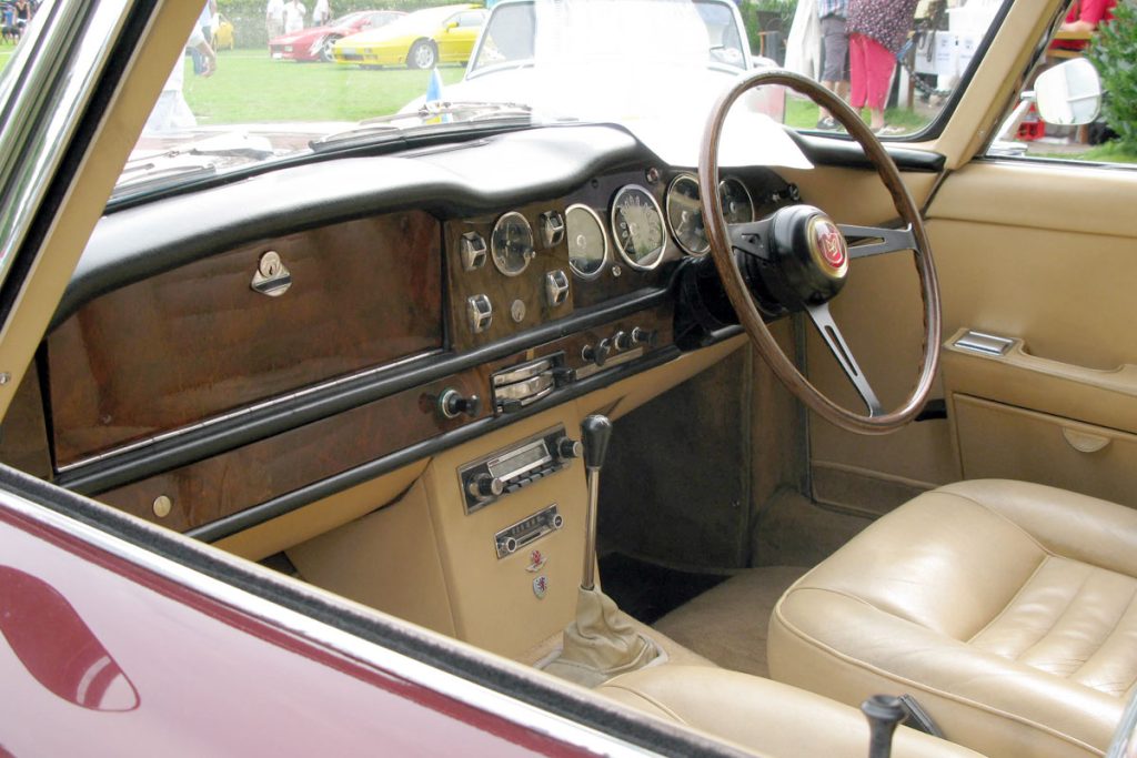 Cream leather interior car cabin with wooden dashboard and steering wheel