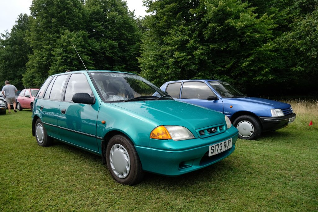 Two cars parked in a field with trees in the background