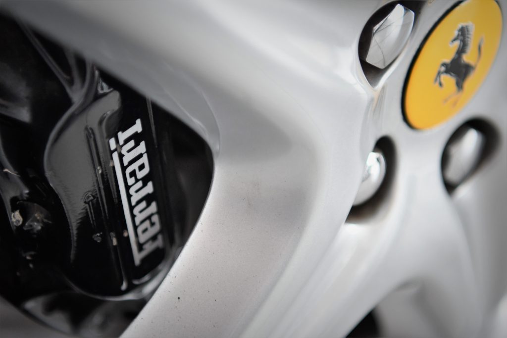 Close up of a silver car alloy and a black brake calliper 