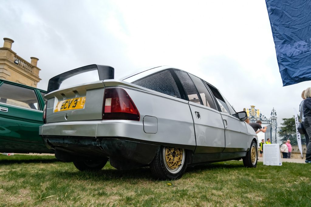 Rear shot of silver car with gold wheels parked on grass
