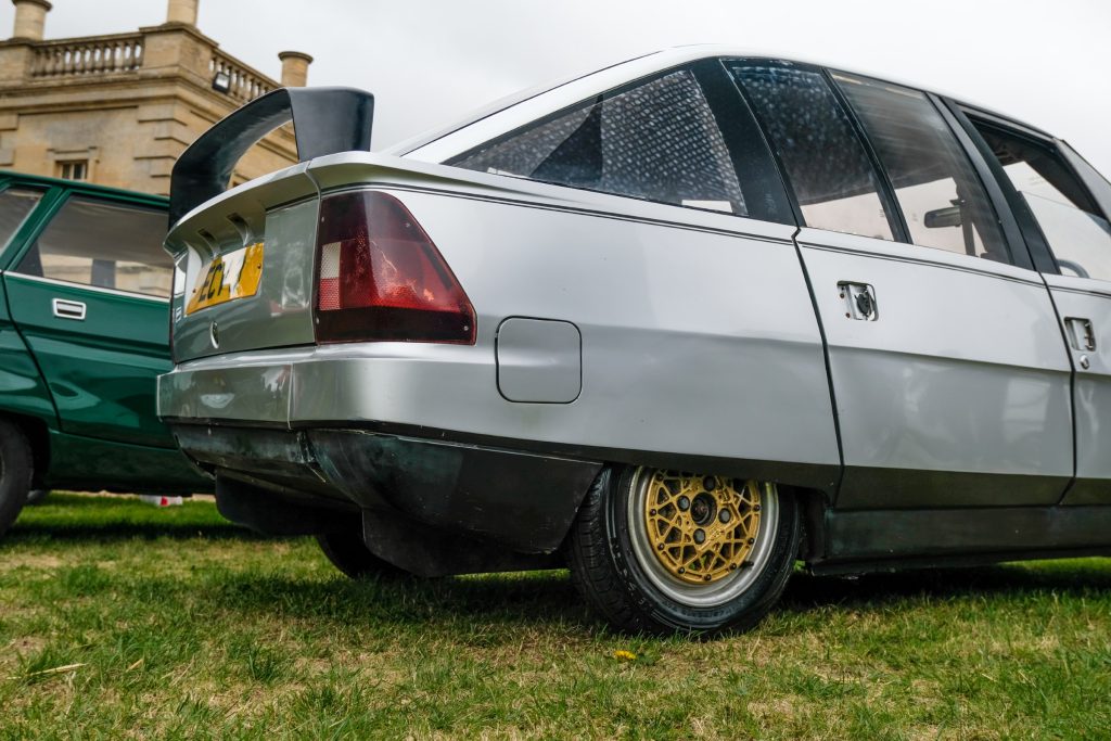 Rear show of silver car with gold wheels parked on grass