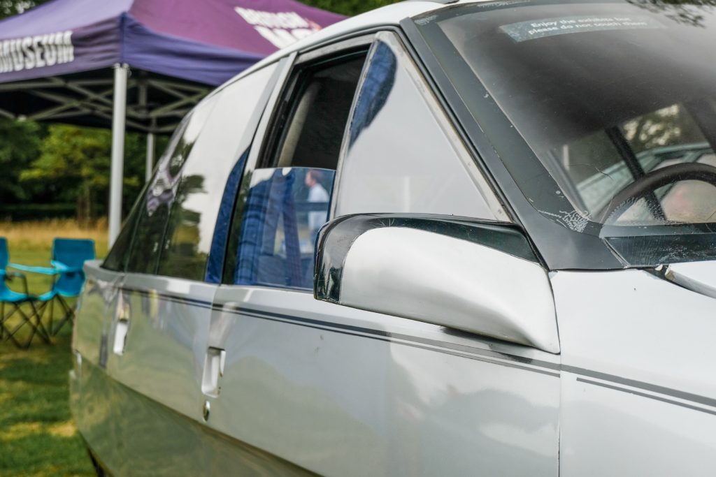 Close-up of silver car wing mirror and open front window
