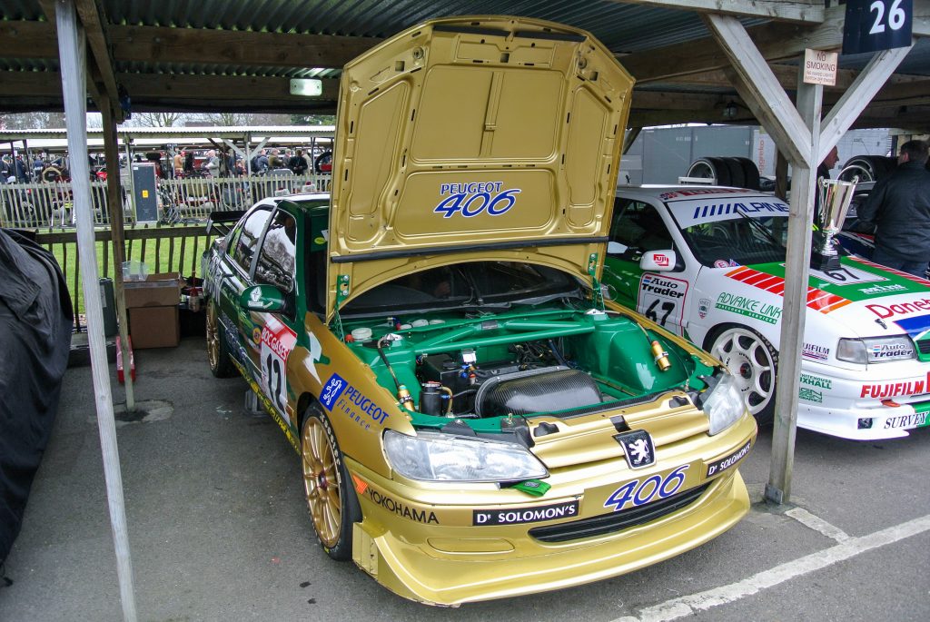 Gold Peugeot 406 BTCC parked in parking bay with bonnet raised exposing engine
