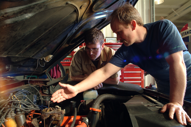 Two mechanics inspecting a classic car for an MOT