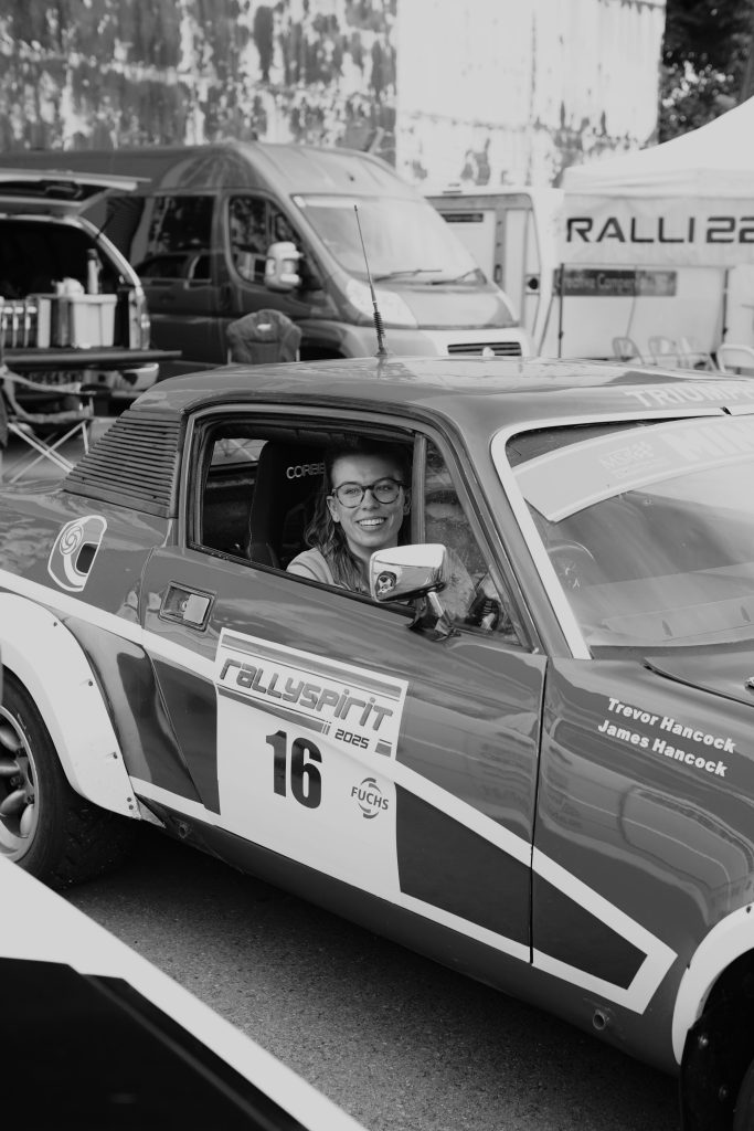 Classic race car parked with an open front window showing a female driver