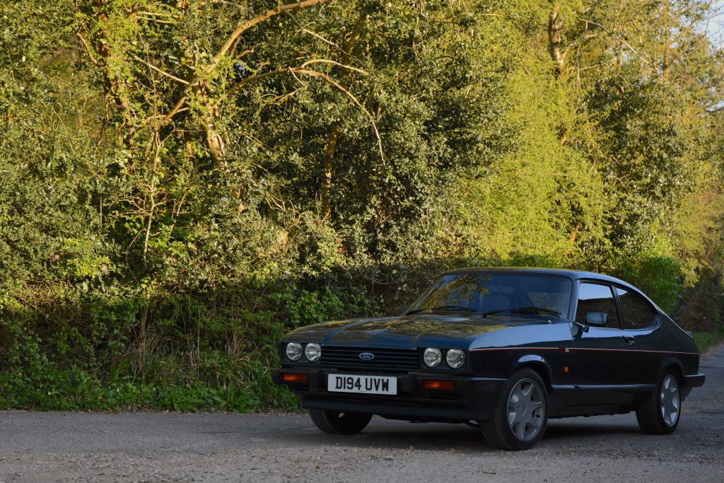 Green Ford Capri 280 parked up in front of trees