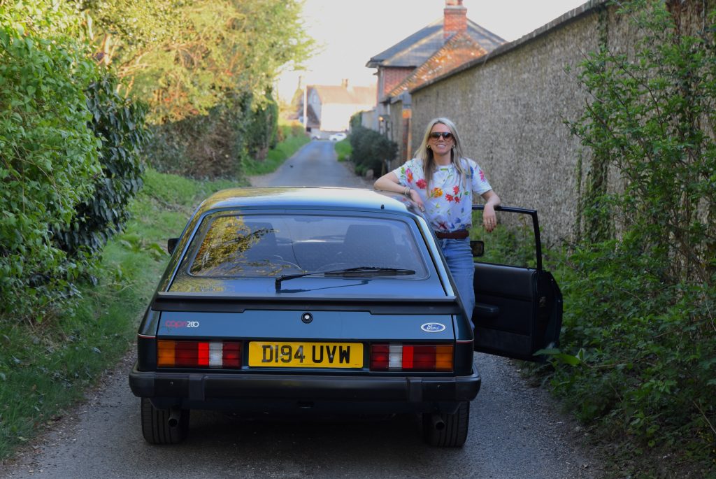 Woman stood next to a green Ford Capri with the door open