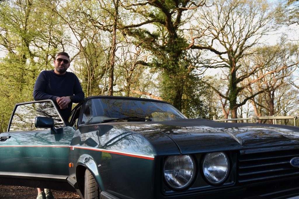 Man stood next to a green car in woodland