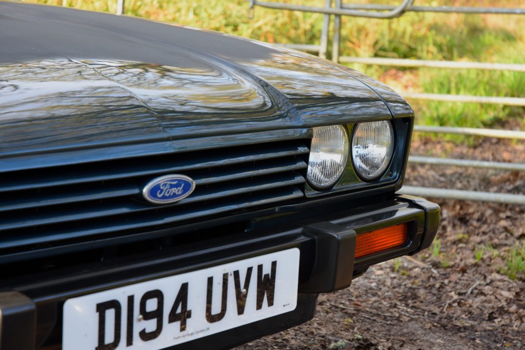 Close up of the front lights and grill of a green Ford Capri
