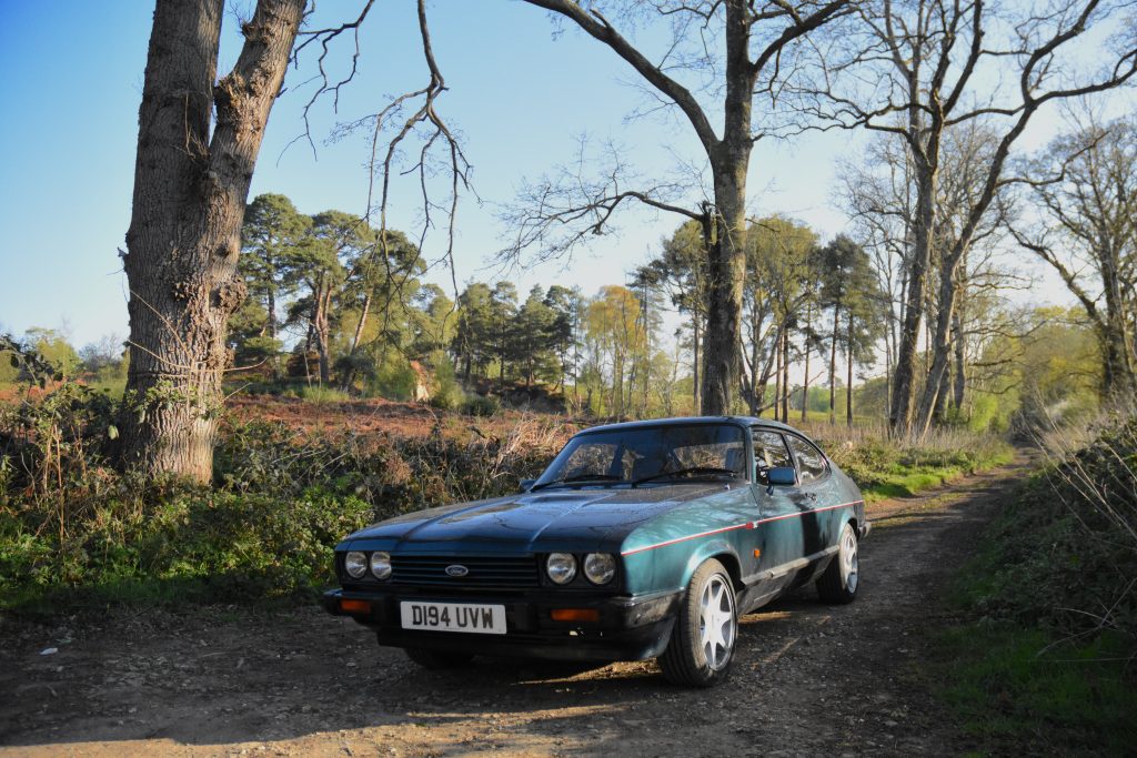 Ford Capri parked on a country road with trees in the background