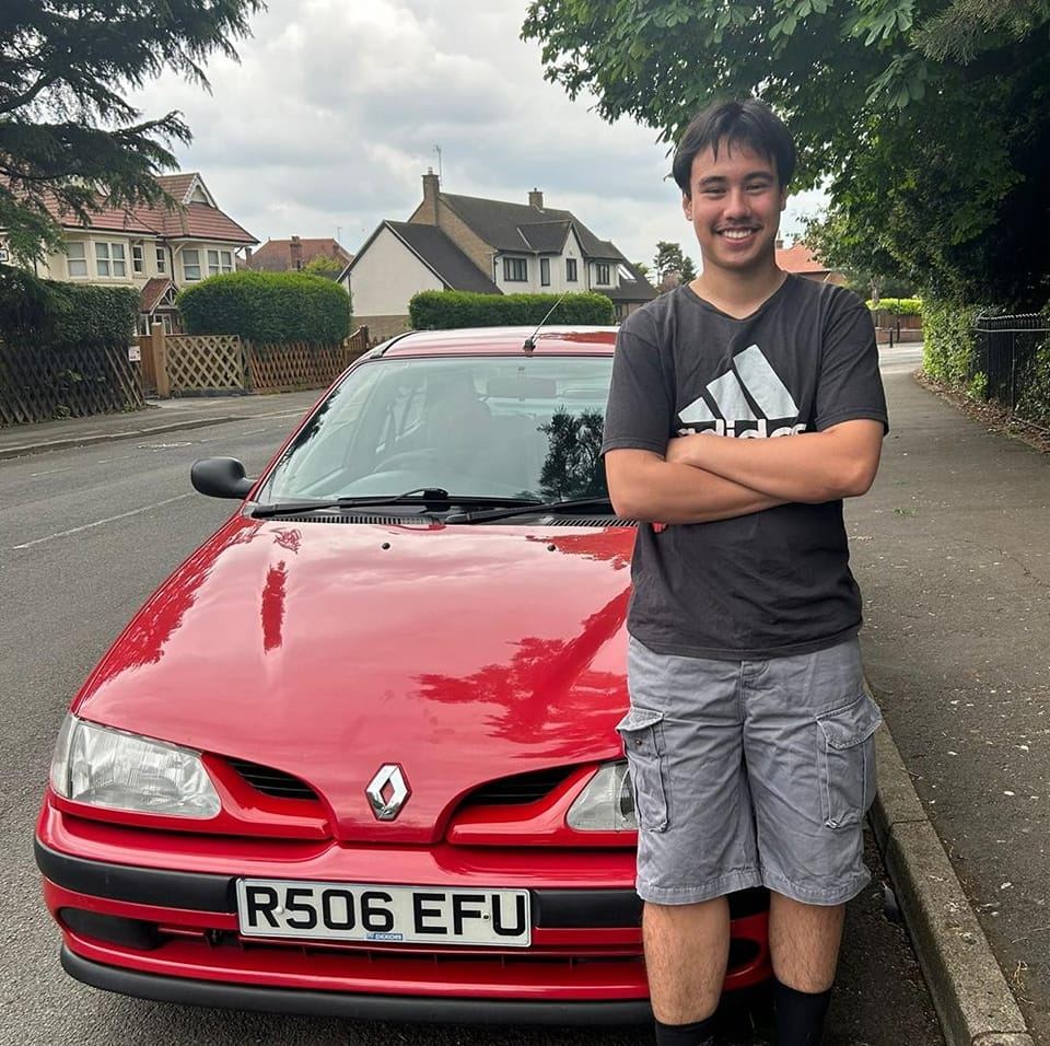 Man stood next to red Renault Megane