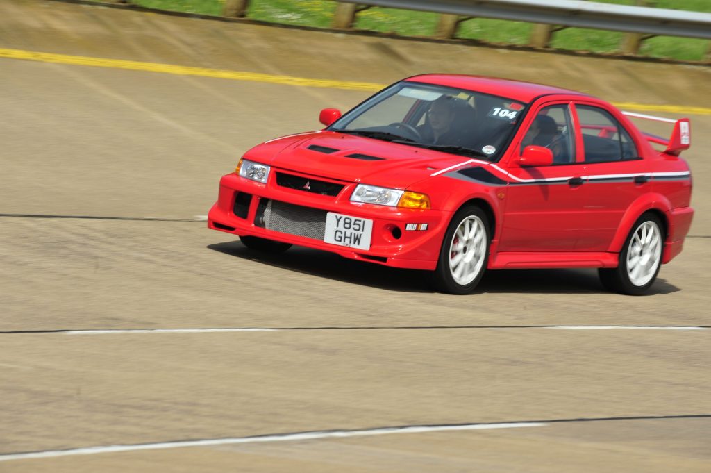 Red Mitsubishi Lancer Evo driving on track
