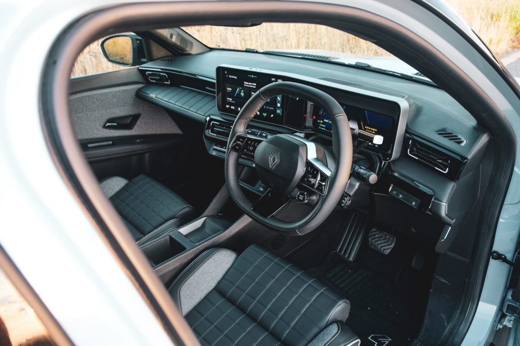 Steering wheel, infotainment system and two front seats of a car with its door open