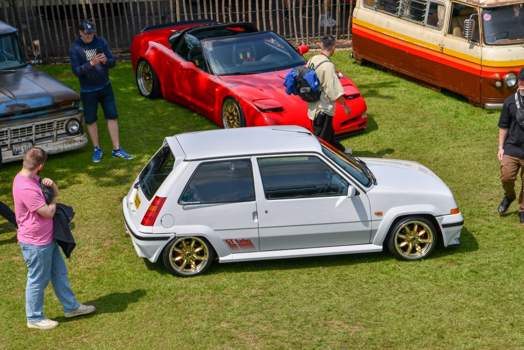 Four cars parked in a field with four men standing around them