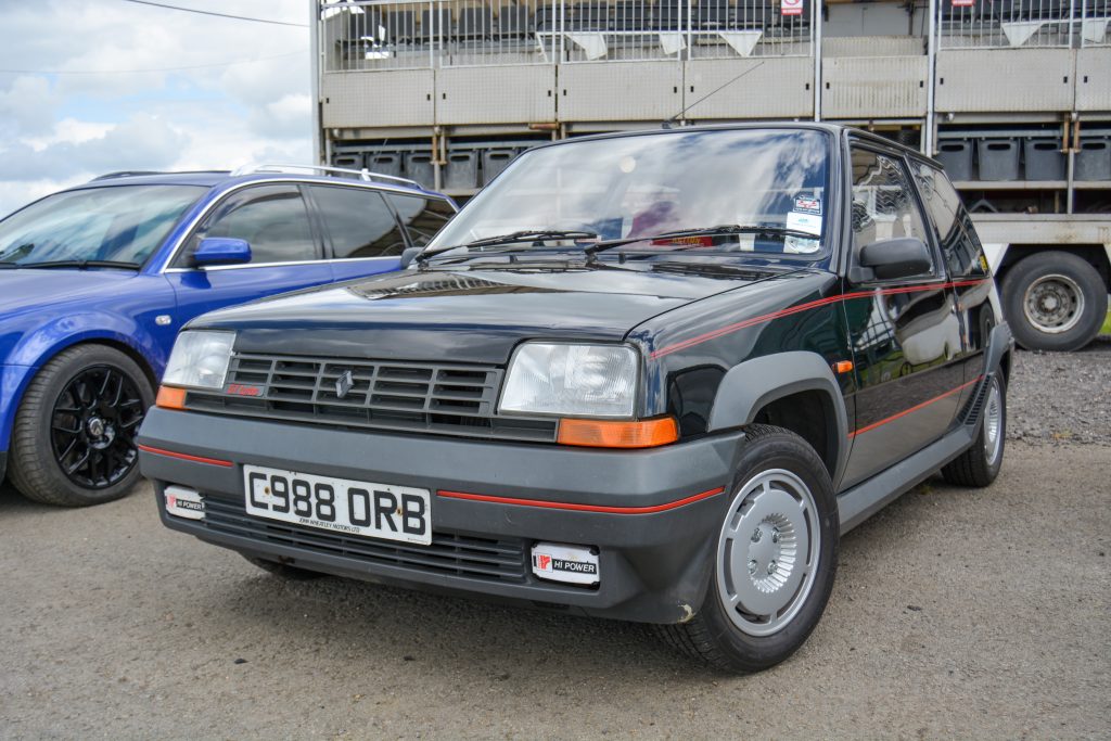 Black Renault car parked up with a lorry in the background