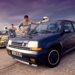 Two Renault 5 GT Turbos parked up in front of sea with two men standing next to them