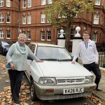 Man and a woman standing next to a white classic car