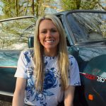 Woman smiling in front of green car