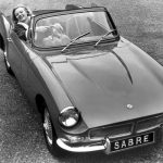 Greyscale shot of a car being driven by a smiling female