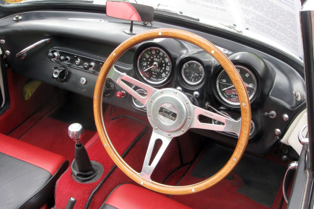 Interior cabin of a car with red leather seats and wooden steering wheel