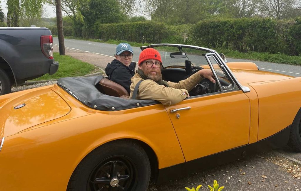 Two people sat in yellow classic car