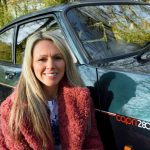 Woman smiling kneeling next to a green car