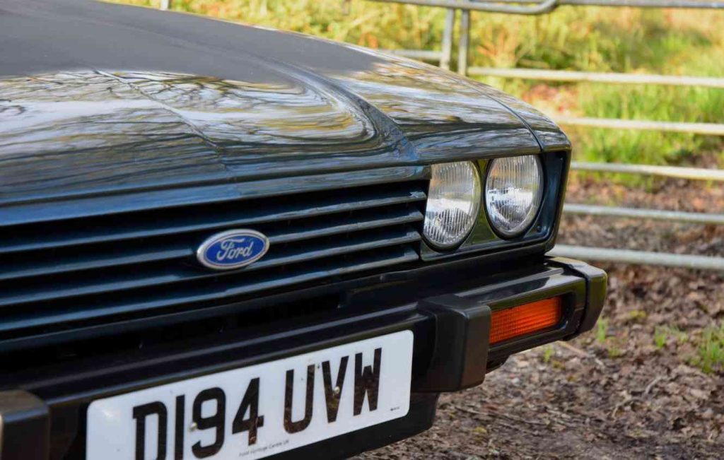Close up of the front lights and grill of a green Ford Capri