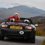 Woman wearing santa hat sat inside parked car