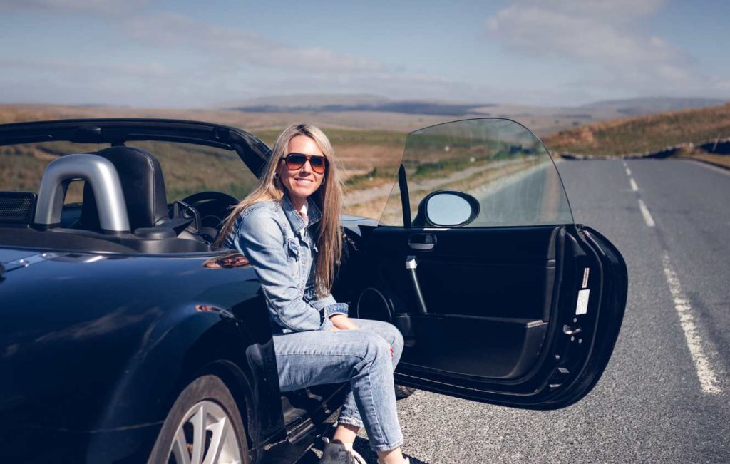 Woman sat in parked car with the door open