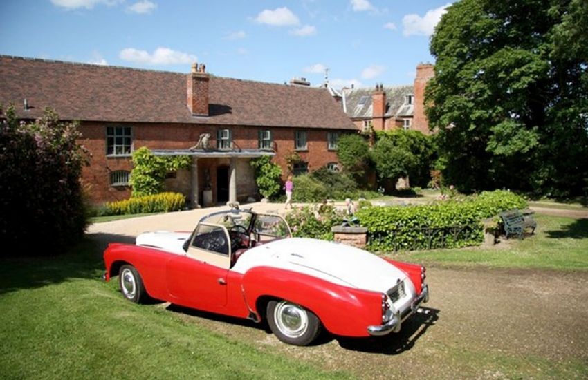 Red and white car parked on the driveway of a red brick house