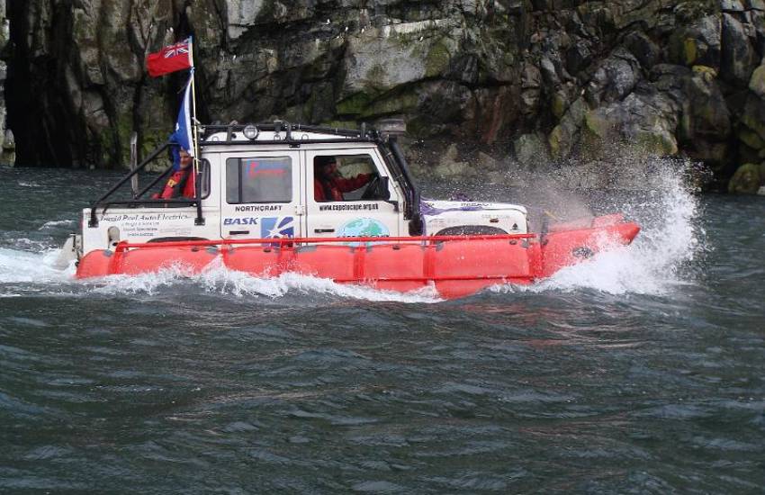 Floating Landrover Defender sailing through choppy water