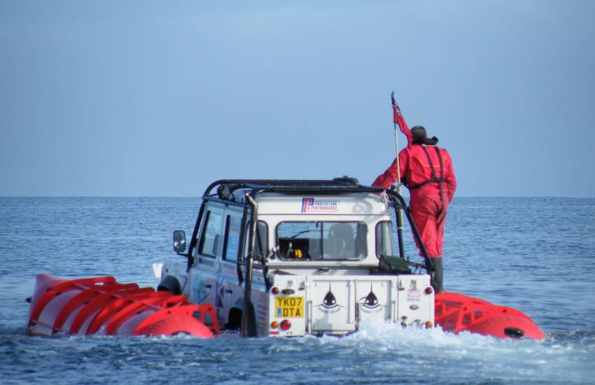 Floating Landrover Defender sailing through choppy water