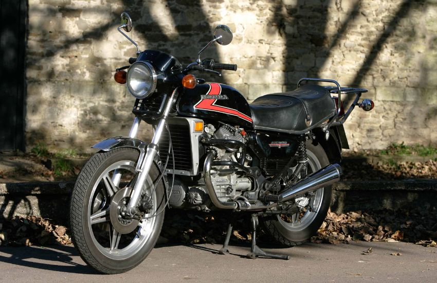Red and black Honda CX500 motorbike parked up in front of a stone wall