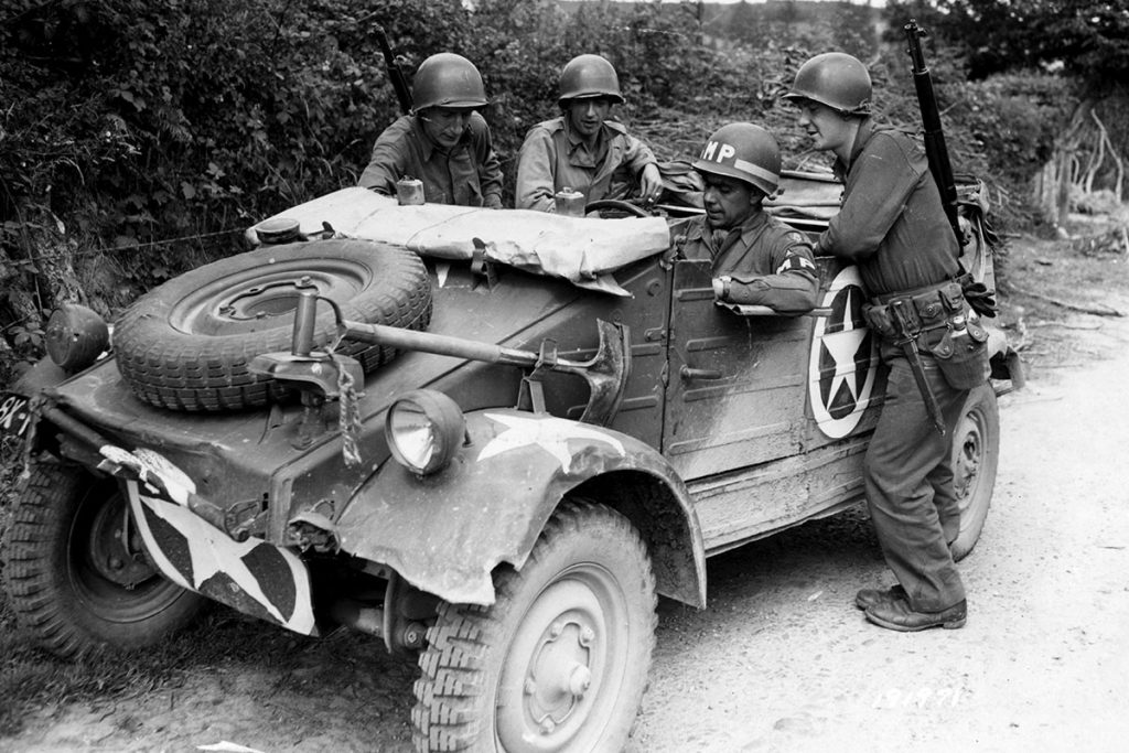 Soldiers standing next to military Volkswagen vehicle