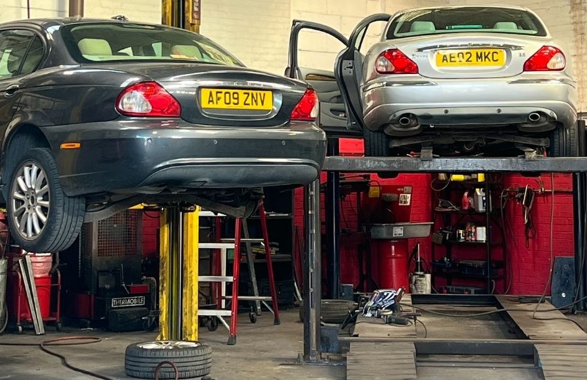 Two cars on jacks in a garage