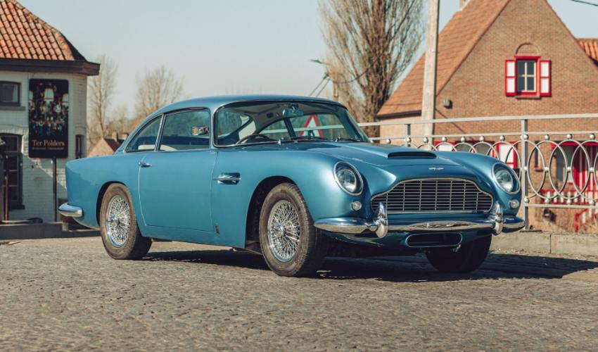 Metallic blue Aston Martin DB5 parked in front of metal railings